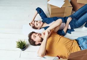 A man and a woman with boxes are moving. Well, an apartment is being renovated by a family photo