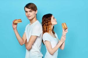 young couple in white t-shirts with hamburgers in their hands fast food snack photo