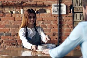 woman waiter brings coffee to a cafe client photo