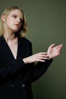 Portrait of a stunning elegant girl in a black suit posing professionally on a green background in the studio. The concept of advertising for designer brands photo