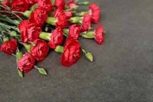 Bouquet of red carnations in top left corner on gray stone background. World War memory symbol. Remember Heroes. Victory Day. Veterans Day. Memorial Day. Greeting card with place for text. photo