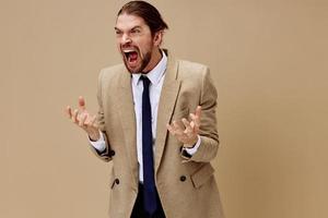 man in beige jacket emotional man in suit gesture with hands beige background photo