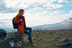 mujer en naturaleza en el montañas se sienta en un Roca y otoño paisaje foto