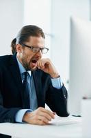 business man in a suit sitting at his desk tired in front of a computer photo