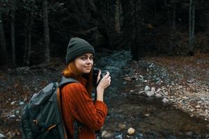 woman with a camera near a pond in the mountains on nature and trees photo