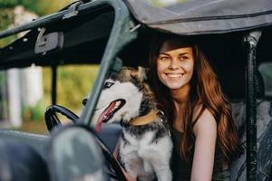 Woman and husky dog happily traveling in car smile with teeth fall walk with pet, travel with dog friend hugs and dances photo