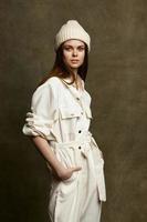 portrait of woman in hat and jumpsuit on brown background cropped view photo