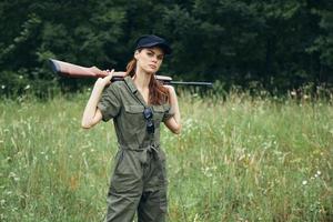 Woman soldier In a green jumpsuit keeps guns on his shoulders a lifestyle green leaves photo