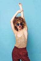 Pretty woman Curly hair hands over head fashionable clothes blue background photo