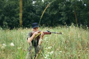 mujer mujer puntería aparte mientras sentado en el suelo en naturaleza armas verde arboles foto