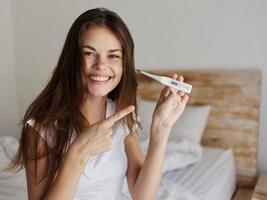 cheerful woman with a thermometer in her hands, a positive result from the temperature photo