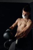 boxer in gloves and medical mask on isolated background looking to the side cropped view photo