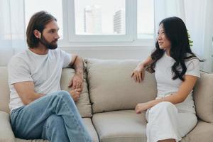 Male and female Asian friends sitting on the couch and having fun talking to each other with a smile having a good time together. Lifestyle in happiness at home photo