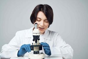 female laboratory assistant looking through a microscope diagnostics research science photo