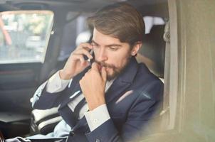 bearded man in a suit in a car a trip to work communication by phone photo