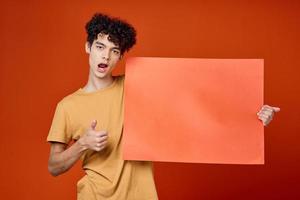guy with curly hair holding a red copy space poster photo