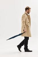 man in an autumn beige coat with an umbrella in his hands protection from the rain modern style photo