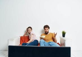 Man and woman on sofa with flower room interior and TV screen photo