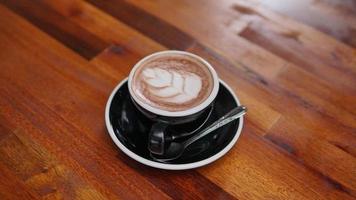 Hot latte art coffee on wooden table in coffee shop, stock photo