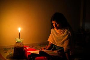 A young girl studying at home with candlelight after electricity load shedding at Dhaka City. photo