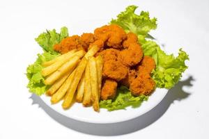 Fresh calamari with french fries in a plate. Healthy sea food squid fry, potato fries and lettuce meal on white background photo