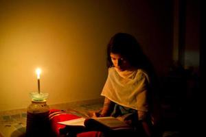 A young girl studying at home with candlelight after electricity load shedding at Dhaka City. photo