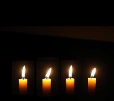 Yellow Candles Burning in the Dark with lights glow. The burning candle's flame in the dark background. a symbol of the Christian faith. photo