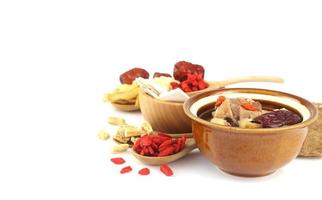 Close up of Chinese herbs clear soup and many herbs on white background photo