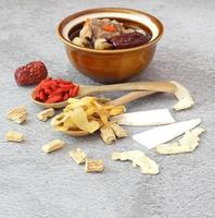 Bowl of chinese herb clear soup with pork and dry herbs on table photo