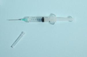 Syringe on a blue background. Syringe with an open cap. Needle. Single medicine object on the blue background with copy space. photo