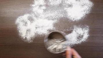 A woman's hand sprinkles flour on the table surface. The view from the top video