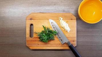 Da donna mani tagliare erbe aromatiche e aglio con un' acuto coltello, su il superficie di il tavolo. il Visualizza a partire dal il superiore video