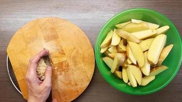 a homem cuidadosamente mistura a cru batatas. temperado com sal e Pimenta. a Visão a partir de a topo. video