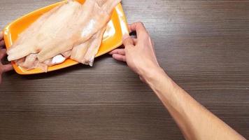 Uomini mani posto un' chopping asse, pesce, e un' cucina coltello su il tavolo. il Visualizza a partire dal il superiore. video