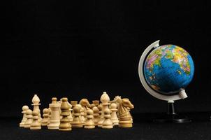 Globe and chess on dark background photo