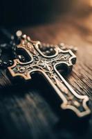 Close-up of a silver cross on a wooden table, shallow depth of field photo