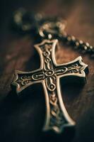 Close-up of a silver cross on a wooden table, shallow depth of field photo