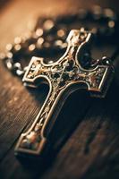 Close-up of a silver cross on a wooden table, shallow depth of field photo