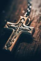 Close-up of a silver cross on a wooden table, shallow depth of field photo