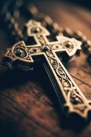 Close-up of a silver cross on a wooden table, shallow depth of field photo