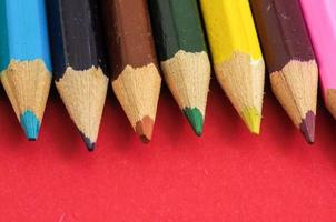 Colorful pencils on red background photo