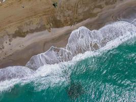 Aerial view of sea crashing waves white foaming waves on seashore rocks top view photo