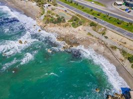 Aerial view of sea crashing waves white foaming waves on seashore rocks top view photo