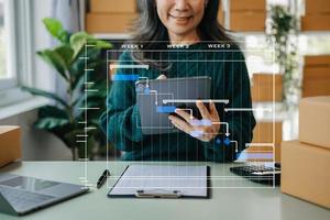 mano de mujer usando una computadora portátil, un teléfono inteligente y una tableta y escribiendo un cuaderno en la oficina de su negocio de compras en línea. en el hogar foto