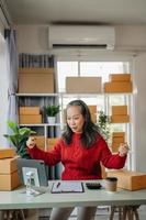 Senior business owner woman prepare parcel box and standing check online orders for deliver to customer on tablet, laptop Shopping Online concept. at home office photo