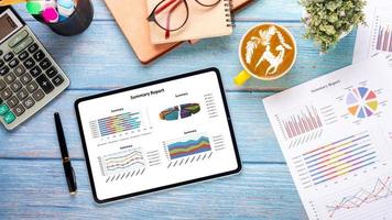 Tablet with charts and reports on office desk workplace. Top view flat lay photo