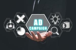 Ad Campaign concept, Business person hand holding ad campaign icon on virtual screen. photo