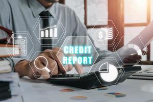 Credit report concept, Businessman using calculator and analyzing business charts on office desk with credit report icon on virtual screen,. photo