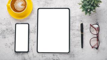 Modern office desk workplace with blank screen tablet and smart phone, pen, eyeglass and cup of coffee, Top view flay lay. photo