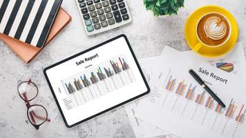 Tablet with charts and reports on office desk workplace. Top view flat lay photo